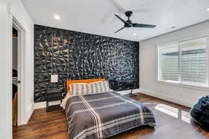 Bedroom with an accent wall, recessed lighting, wood finished floors,