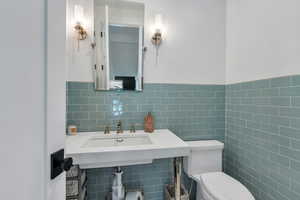 Bathroom with wainscoting, toilet, and tile walls
