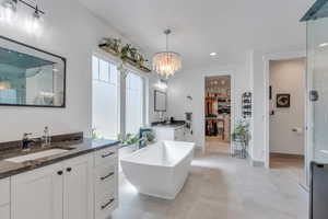 Master bath with a freestanding tub, two vanities, a shower stall, a sink, and a notable chandelier