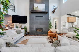 Living area featuring a fireplace, wood finished floors, and a towering ceiling
