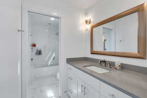 Bathroom with vanity, marble finish floor, tub / shower combination, and toilet
