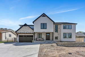 Modern inspired farmhouse featuring board and batten siding, driveway, metal roof,