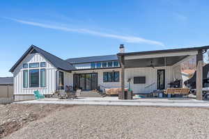 Back of property with board and batten siding, an outdoor living space, a ceiling fan, , and a patio