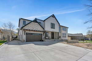 View of front of property with board and batten siding, driveway, stone siding,