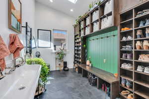 Mudroom featuring recessed lighting, high vaulted ceiling, a skylight, and baseboards