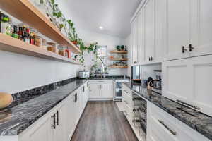 Kitchen featuring white cabinets, open shelves, dark wood finished floors, dark stone countertops, and wine cooler