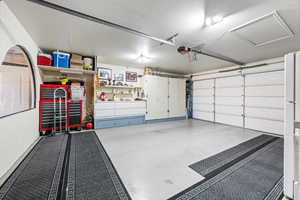 Garage featuring a garage door opener and freestanding refrigerator