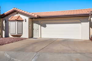 View of front of home featuring a tiled roof, driveway, and stucco siding