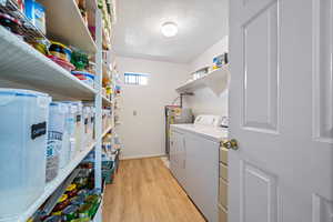 Laundry room with laundry area, light wood finished floors, a textured ceiling, baseboards, and washing machine and dryer