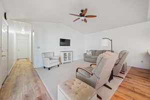 Living area with baseboards, ceiling fan, vaulted ceiling, and light wood-style flooring