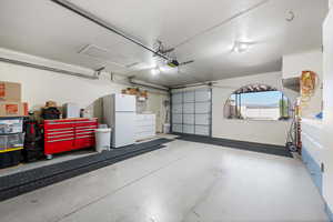 Garage featuring freestanding refrigerator and a garage door opener