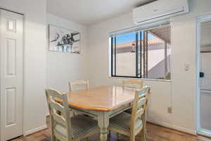 Dining room featuring wood finished floors, baseboards, and a wall mounted AC