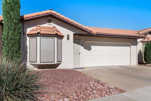 Ranch-style house featuring an attached garage, stucco siding, a tiled roof, and concrete driveway