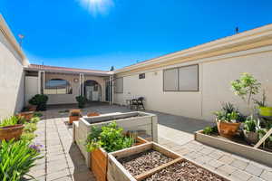Back of property with a patio, a garden, stucco siding, and a tile roof