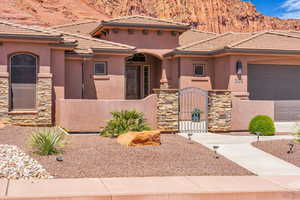 View of front of house with a fenced front yard, stone siding, and stucco siding