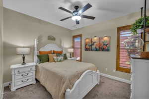 Bedroom with a ceiling fan, baseboards, and light carpet
