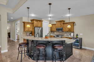 Kitchen with beverage cooler, stone tile floors, brown cabinets, and stainless steel appliances