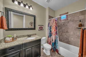 Bathroom featuring visible vents, tile patterned flooring, vanity, toilet, and shower / tub combo