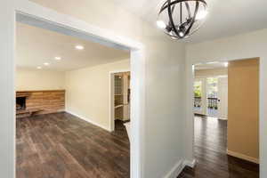 Hall with an inviting chandelier, recessed lighting, dark wood finished floors, and baseboards