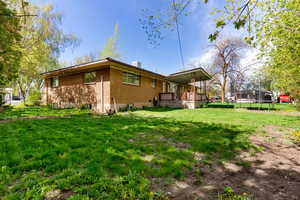 Rear view of house with central AC, brick, a lawn,  and a covered porch