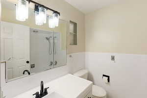 Bathroom with tile walls, wainscoting, vanity, toilet, and washtub / shower combination