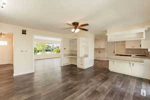 Dining area featuring  dark wood -like floors, a sink, baseboards, and ceiling fan with notable chandelier
