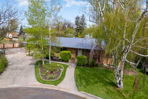 Ranch-style home featuring brick siding, driveway, metal roof, and a front lawn