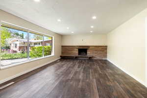 Unfurnished living room with a stone fireplace,  wood like floors, baseboards, and recessed lighting