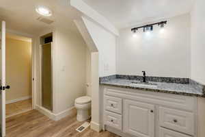 Full bath featuring toilet, visible vents, a shower stall, and wood finished floors, includes laundry hookups