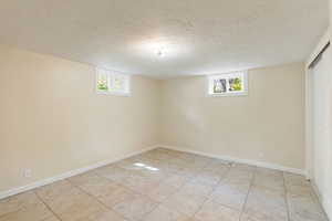 Bedroom featuring light tile patterned flooring, a textured ceiling, plenty of natural light, and baseboards