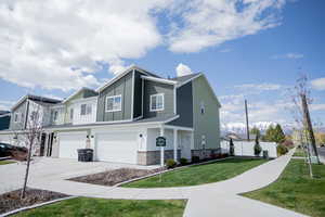 View of home's exterior with a lawn, fence, stone siding, concrete driveway, and an attached garage