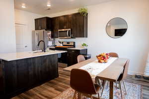 Kitchen featuring dark brown cabinets, appliances with stainless steel finishes, light countertops, dark wood finished floors, and visible vents
