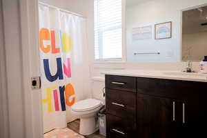 Full bath with vanity, toilet, a shower with shower curtain, wood finished floors, and visible vents