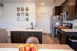 Kitchen with a sink, appliances with stainless steel finishes, dark brown cabinetry, and dark wood-type flooring