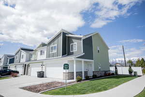 View of front facade featuring a garage, fence, a front yard, stone siding, and driveway