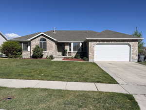 Single story home with brick siding, a garage, a front lawn, and concrete driveway