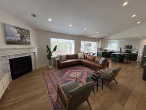 Living room featuring light wood-style floors, plenty of natural light, vaulted ceiling, and recessed lighting