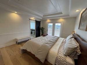 Bedroom featuring access to outside, a barn door, crown molding, and a tray ceiling