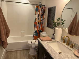 Bathroom featuring vanity, toilet, wood finished floors, and shower / tub combo with curtain