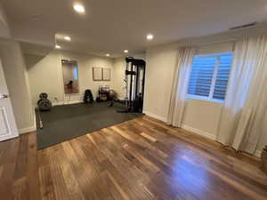 Exercise room with recessed lighting, baseboards, visible vents, and wood finished floors