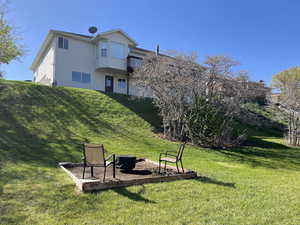 Rear view of property featuring a lawn, an outdoor fire pit, and a balcony