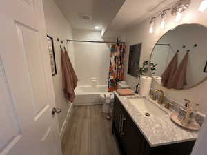 Full bathroom featuring shower / bath combination with curtain, visible vents, wood finished floors, vanity, and toilet