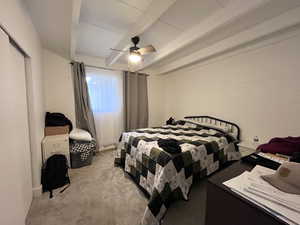 Bedroom with concrete block wall, ceiling fan, and light colored carpet