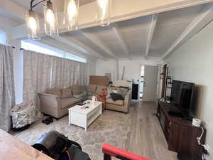 Living area with beamed ceiling, an inviting chandelier, and light wood-type flooring