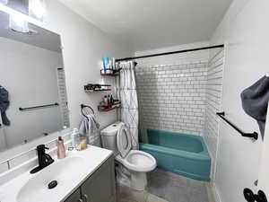 Bathroom featuring vanity, shower / tub combo with curtain, tile patterned floors, and toilet
