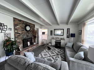 Carpeted living room featuring beam ceiling and a fireplace
