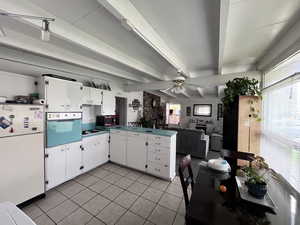 Kitchen featuring plenty of natural light, freestanding refrigerator, a peninsula, wall oven, and light tile patterned floors