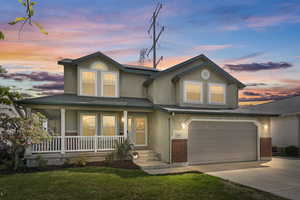 View of front of home with an attached garage, a front yard, stucco siding, a porch, and driveway