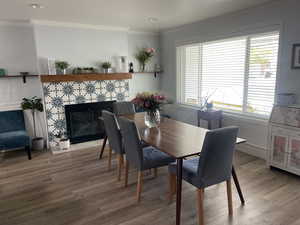 Dining space featuring a tiled fireplace, ornamental molding, and wood finished floors