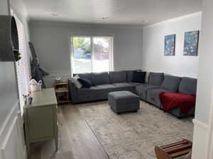 Living area with crown molding, a wainscoted wall, a decorative wall, and wood finished floors